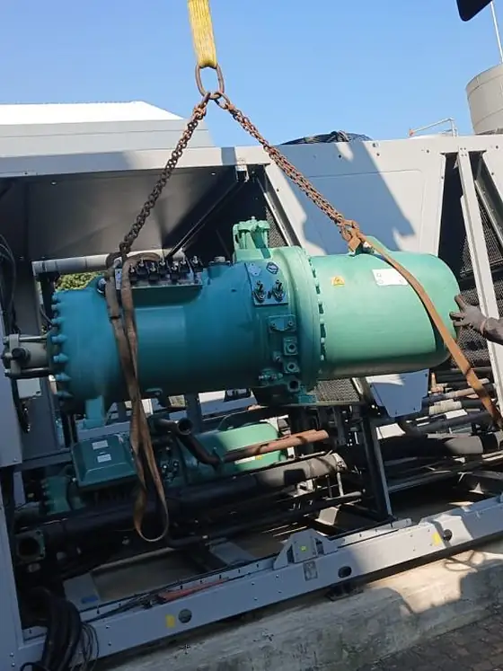 A compressor suspended from a gantry during rigging
