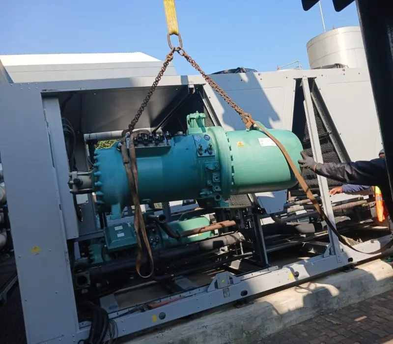 A compressor suspended from a gantry during rigging
