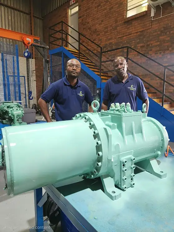 A semi-hermetic screw compressor mounted on a workshop bench