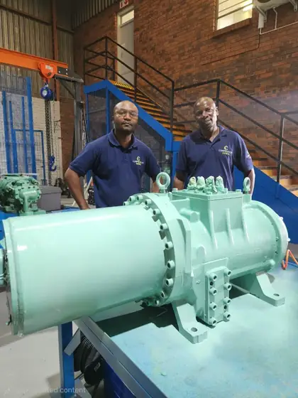 A semi-hermetic screw compressor mounted on a workshop bench