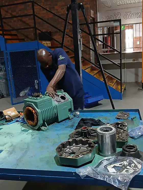 A compressor stripped down with components laid out on the bench