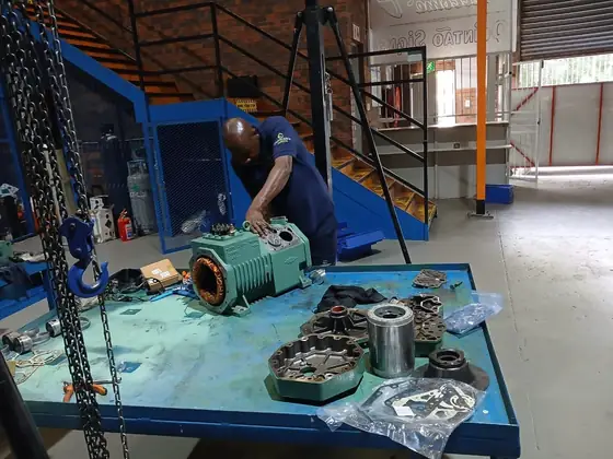 A compressor stripped down with components laid out on the bench